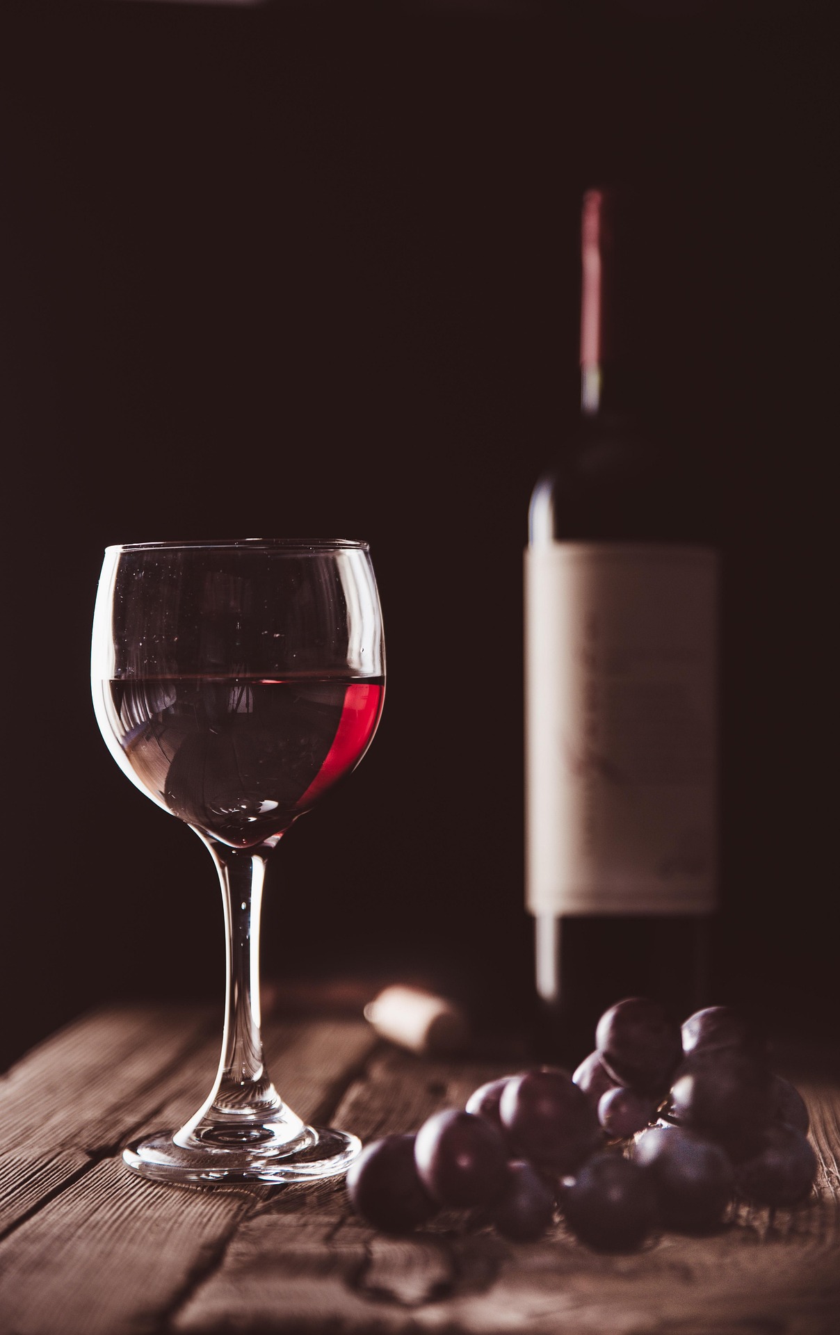 photo of a wine bottle, a bunch of grapes, and a glass of wine